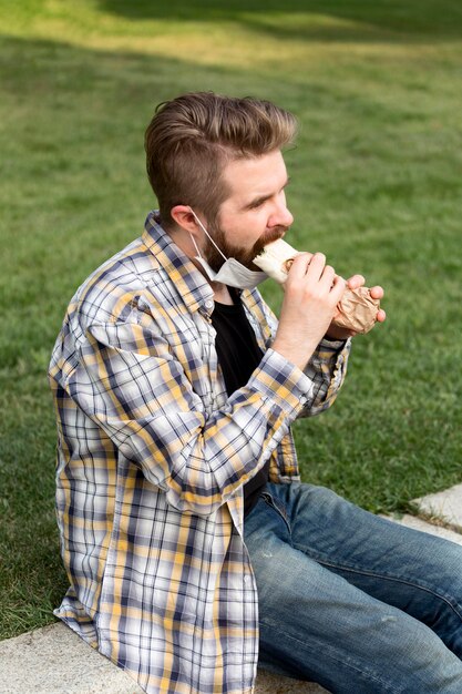 Вид сбоку молодой мужчина ест фаст-фуд