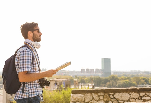 Side view of a young male hiker with map