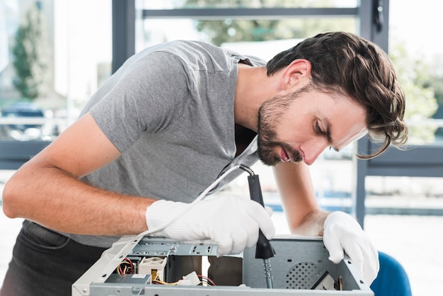 Side view of a young male technician working on broken computer