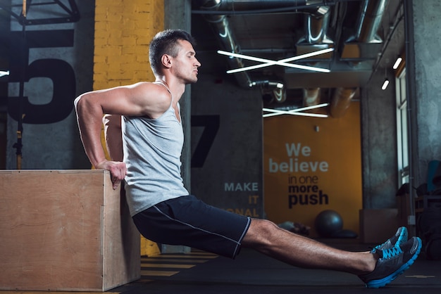 side view of a young man exercising in gym