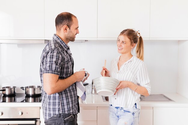 彼の妻が台所で食べ物を準備するのを助ける若い男の側面図