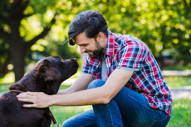 彼の犬を見ている若い男の側面図