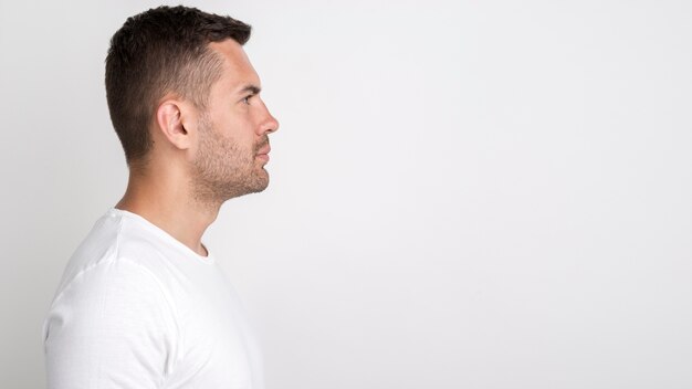 Side view of young man standing against white background