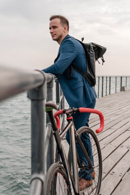 屋外で彼の自転車の横に立っている側面図若い男