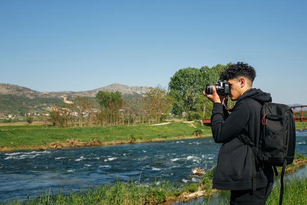 Взгляд со стороны молодого человека используя камеру dslr фотографируя