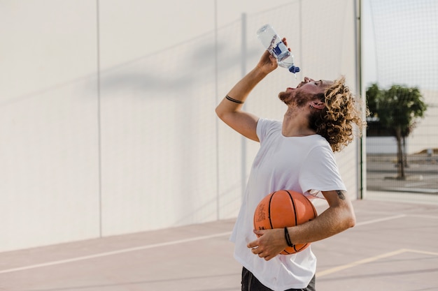 Side view of a young man with basketball drinking water