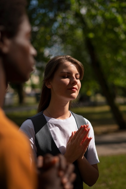side view young people praying outdoors