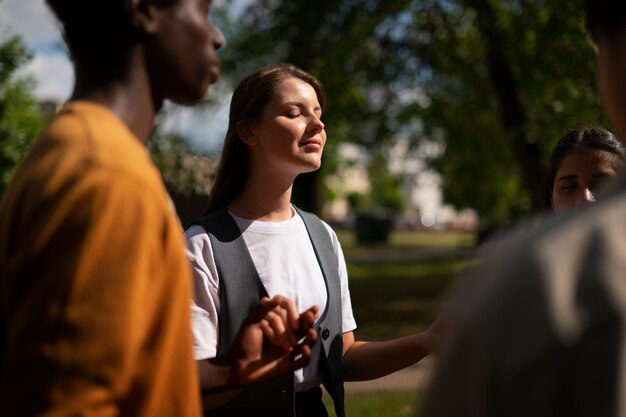 side view young people praying outdoors