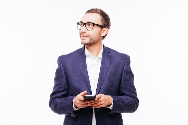 Side view of young stylish man in jeans using mobile phone isolated over white wall