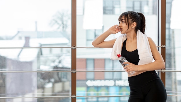 Side view young woman on break at gym