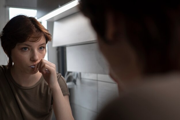 Side view young woman brushing teeth