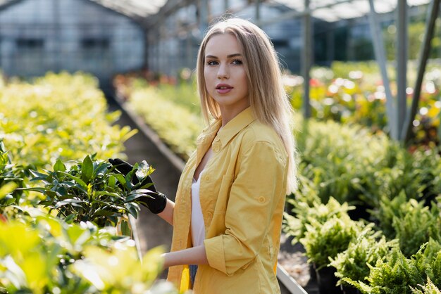 Вид сбоку молодая женщина ухаживает за растениями