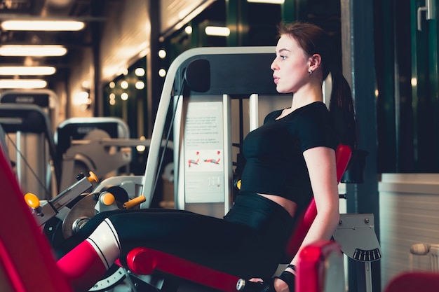 Side view of a young woman doing leg press exercise