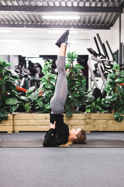 Side view of a young woman doing leg up exercise on yoga mat