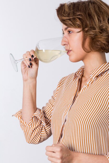 Взгляд со стороны молодой женщины выпивая вино изолированное на белой предпосылке