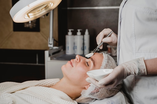 Side view of young woman getting a face skin treatment at the spa