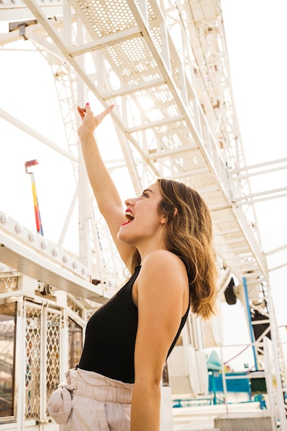 Free photo side view of young woman making fun at amusement park