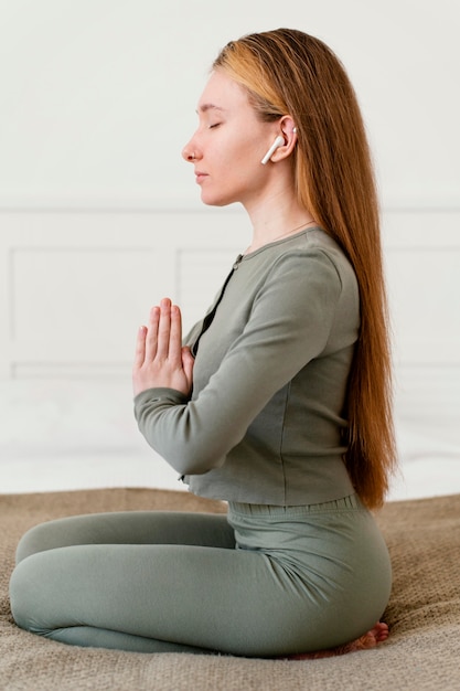 Free photo side view young woman meditating at home