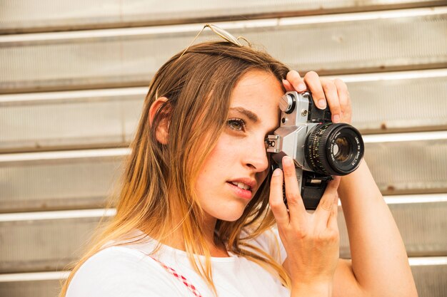 Side view of young woman photographing with digital camera