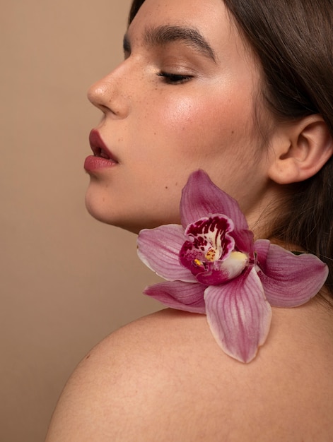 Foto gratuita giovane donna di vista laterale che posa con il fiore