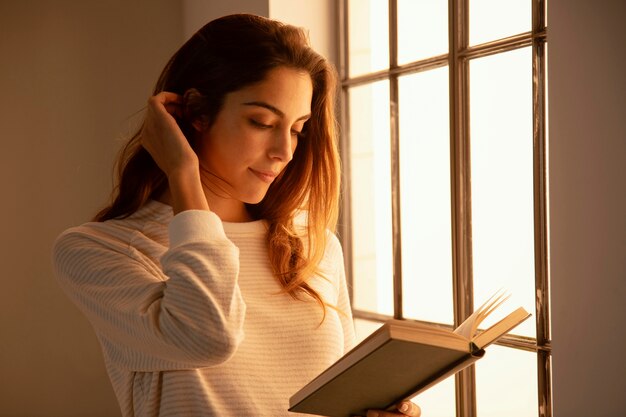 Side view of young woman reading a book at home