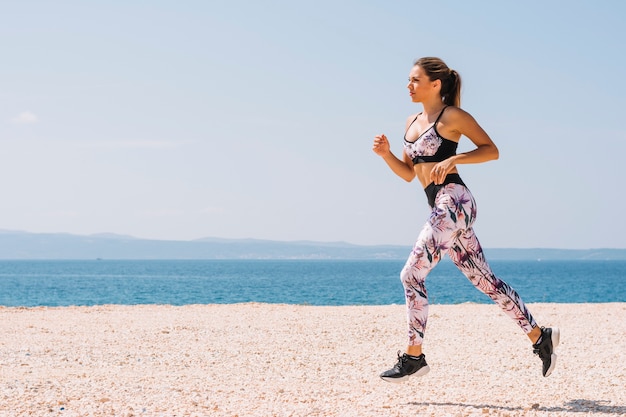 Side view of a young woman running on beach