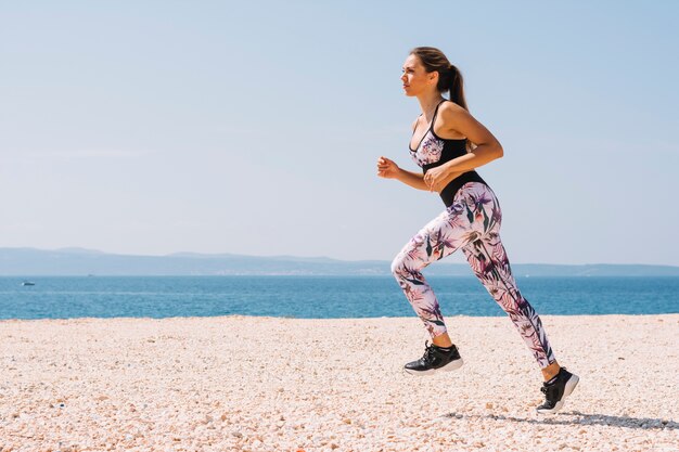 Side view of a young woman running on beach