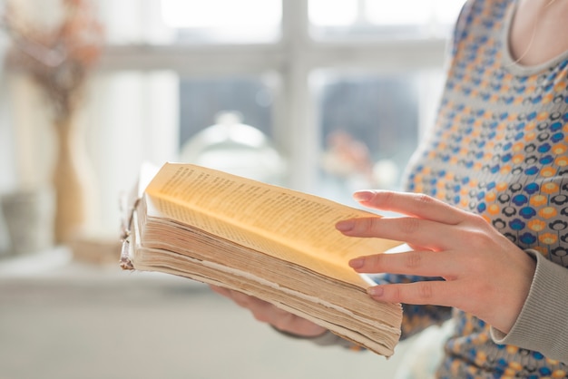 Side view of young woman's hand turning the pages of book