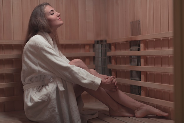 Foto gratuita vista laterale della giovane donna che si siede sul banco di legno nella sauna