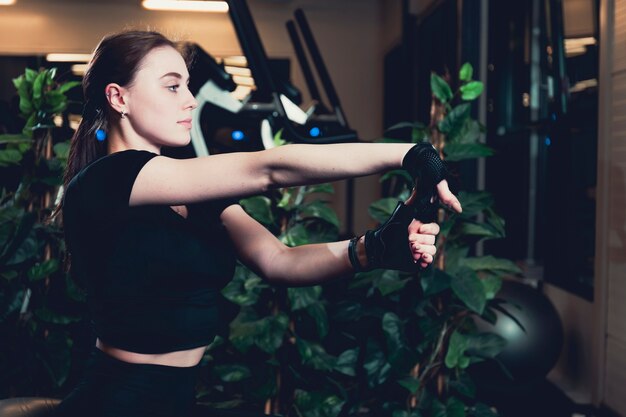 Side view of a young woman stretching at gym