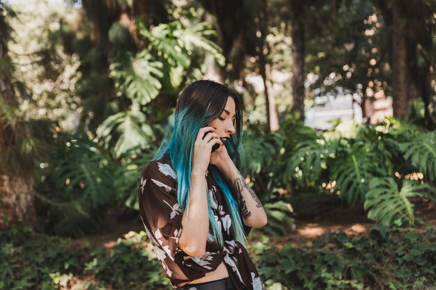 Вид сбоку молодая женщина, говорить на мобильный телефон в парке