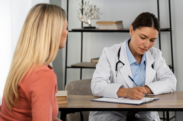 Side view young woman talking to doctor