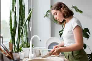 Free photo side view young woman washing dishes