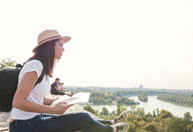 Side view of young woman with map looking at view