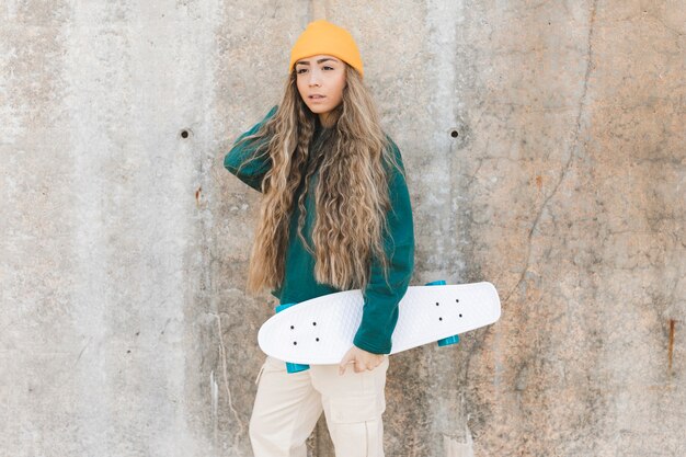 スケートボードを持つ側ビュー若い女性