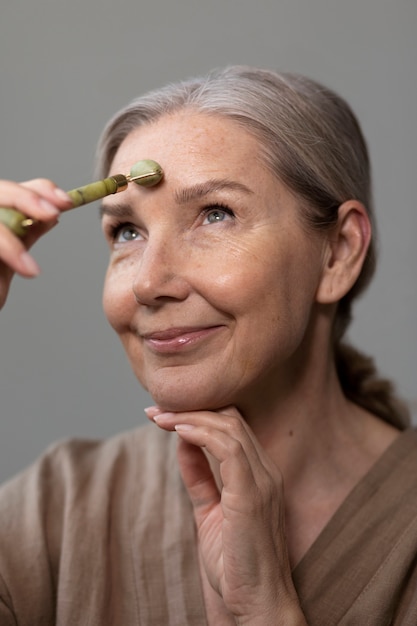 Foto gratuita donna senior di vista laterale che massaggia il viso