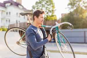 Free photo sideview casual male carrying bicycle