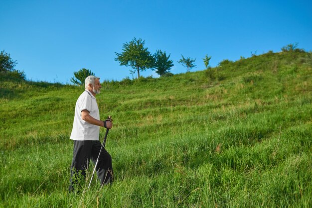 山で追跡棒を持って歩く老人の側面図