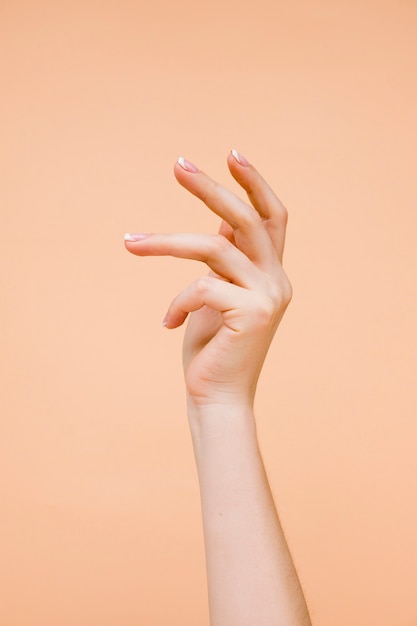 Sideview woman's hand on pale orange background