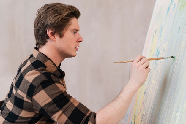 Sideways artist man painting on canvas