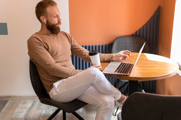 Sideways bearded man working on laptop