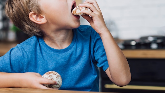 Ragazzo lateralmente che mangia un biscotto