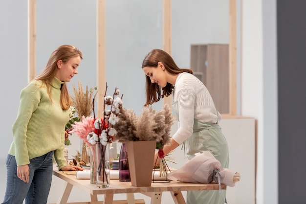 Free photo sideways business women arranging the flower shop