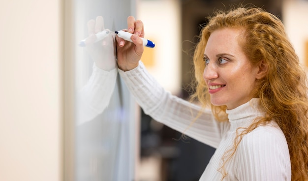 Sideways businesswoman writing with a marker