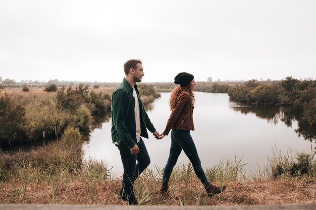 Sideways couple walking next to a pond