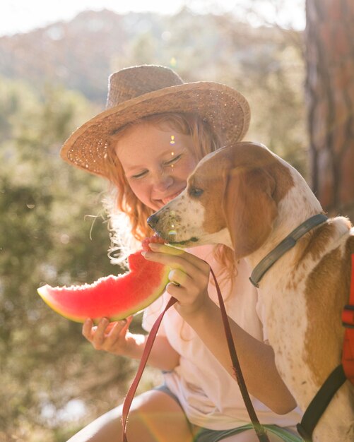 横向きの犬とスイカのスライスを食べる女性