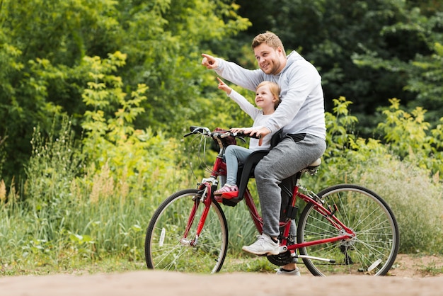 Sideways father and daughter on bicycle