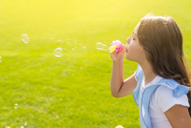 Sideways girl making soap bubbles outside