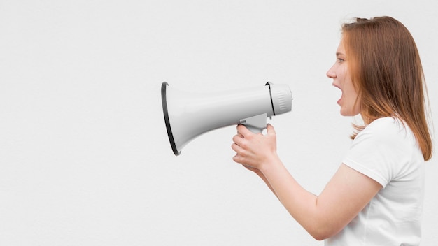 Free photo sideways girl screaming in megaphone