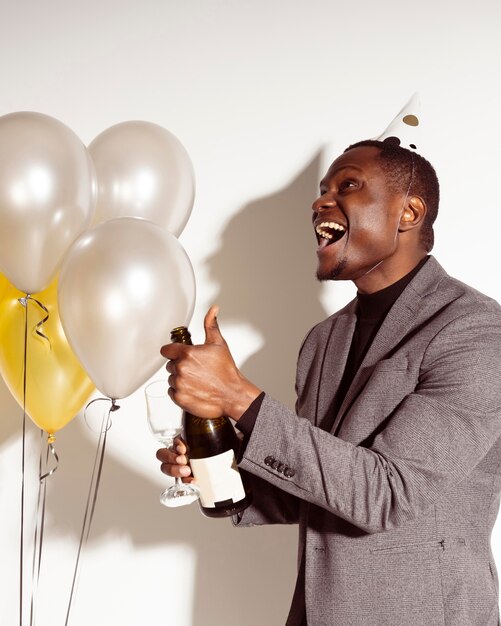 Sideways happy man opening a bottle of champagne